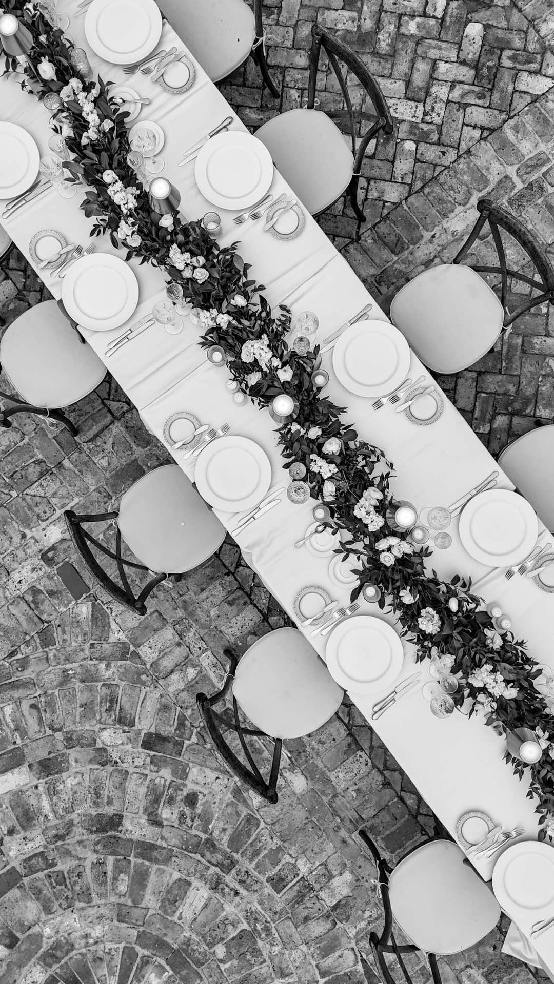 Overhead black and white photography of elegant wedding reception table with floral centerpiece